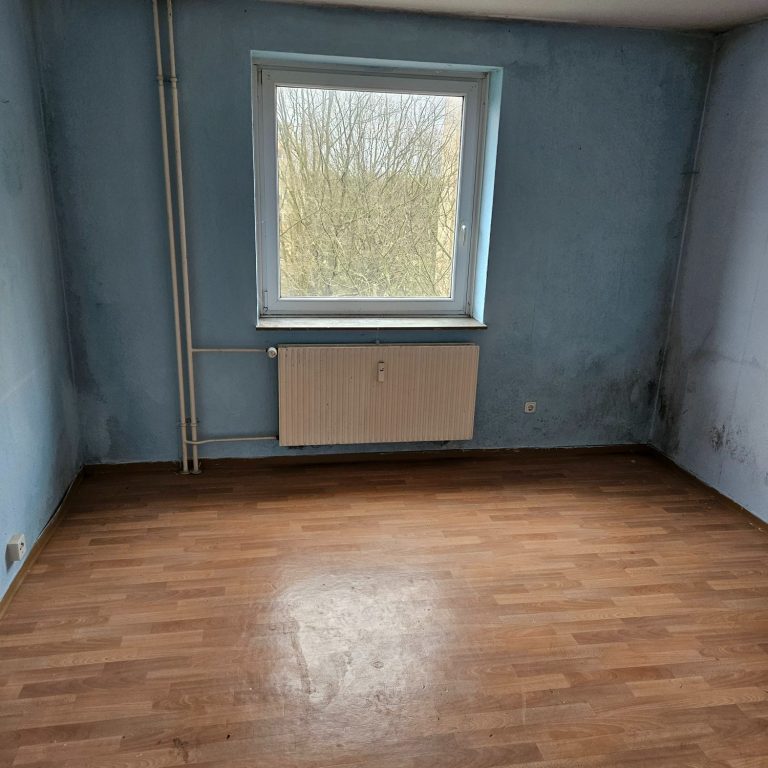 Leeres Zimmer mit einem Fenster und einem Heizkörper.