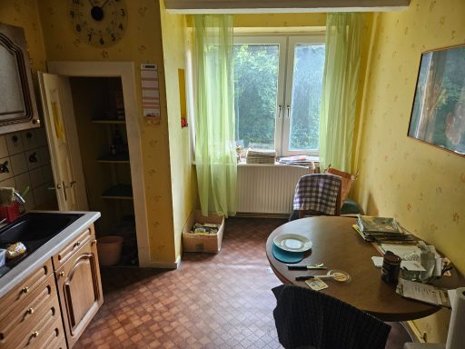 Helle Küche mit gelben Wänden, Tisch, Stühlen und Blick auf einen Garten.